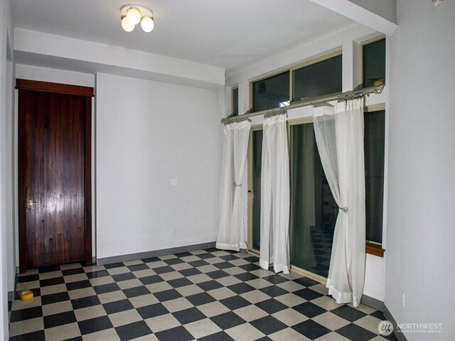 unfurnished room with tile patterned floors and baseboards