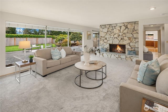 carpeted living room with a stone fireplace