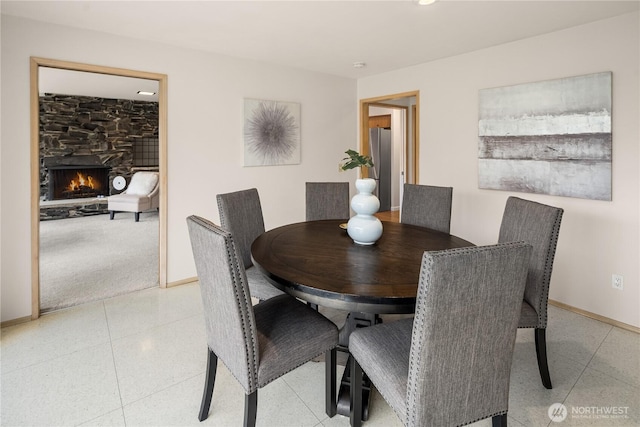 dining area featuring a stone fireplace and baseboards