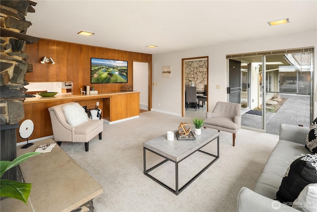 carpeted living room with wooden walls and baseboards