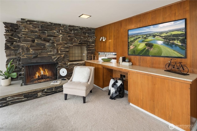 sitting room featuring carpet floors, a fireplace, built in desk, and wood walls