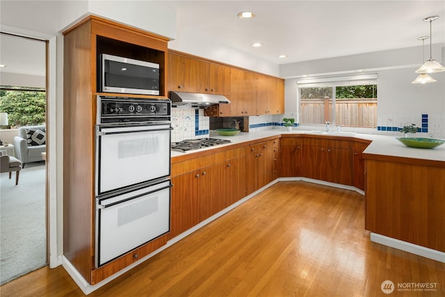 kitchen with under cabinet range hood, appliances with stainless steel finishes, a wealth of natural light, and a sink