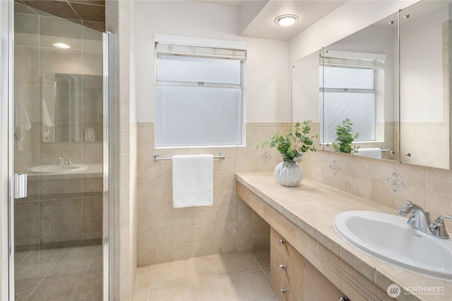 bathroom featuring tile patterned flooring, a stall shower, vanity, and tile walls