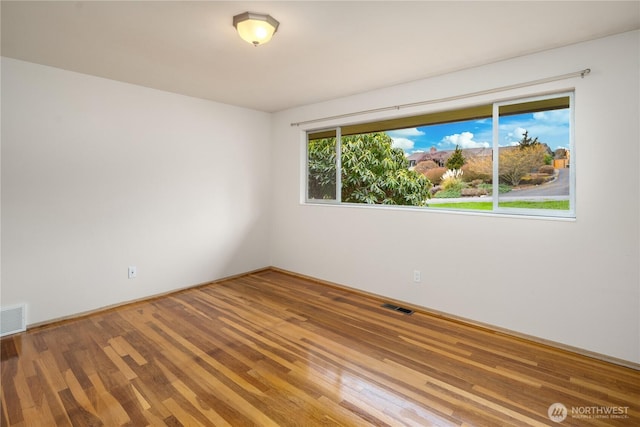 spare room featuring visible vents and wood finished floors