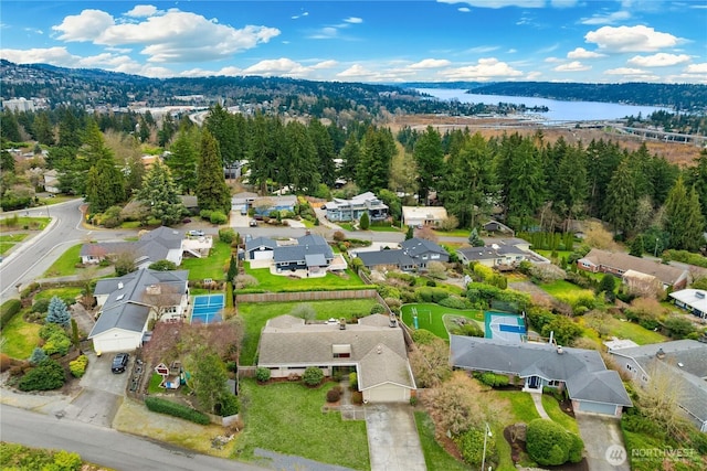 drone / aerial view with a residential view, a wooded view, and a water view