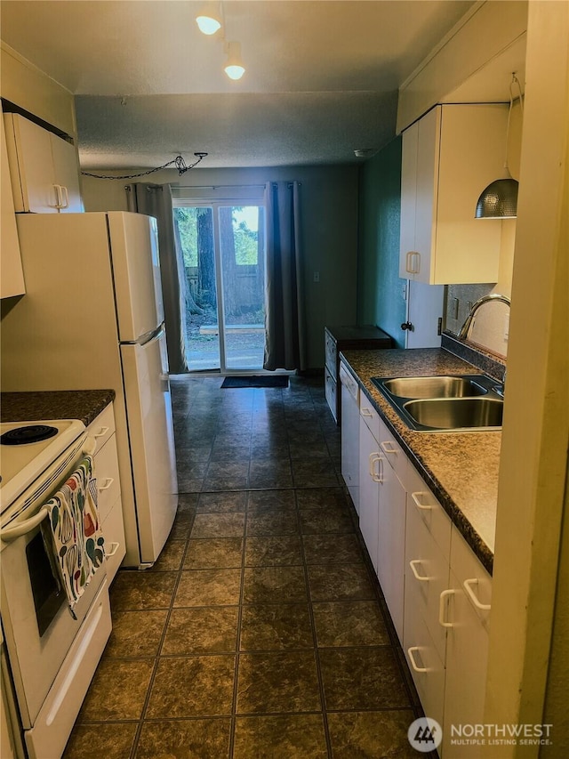 kitchen featuring white appliances, white cabinets, dark countertops, and a sink