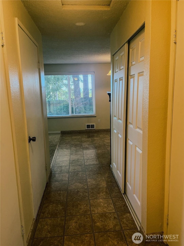 hall featuring visible vents and a textured ceiling