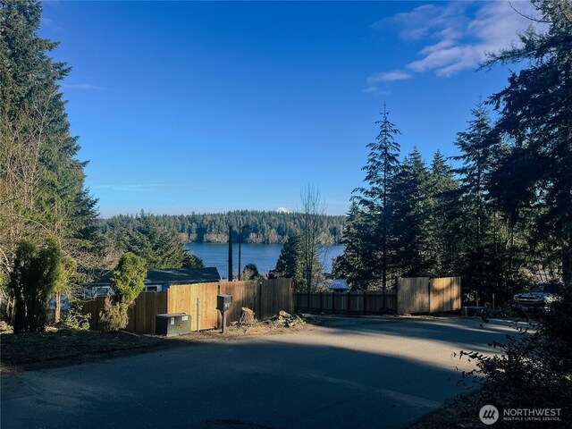 exterior space with a wooded view, fence, and a water view