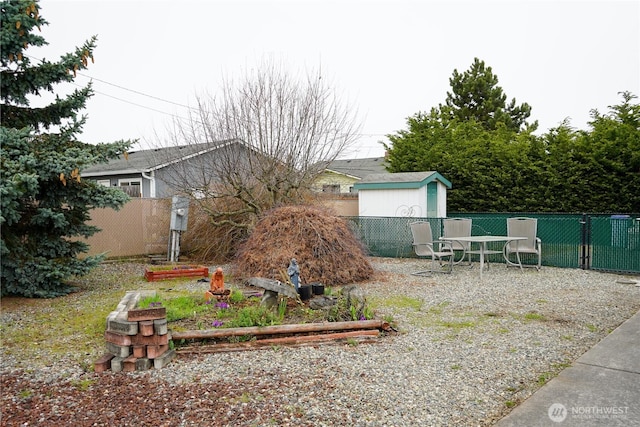 view of yard featuring a storage unit, an outdoor structure, and fence