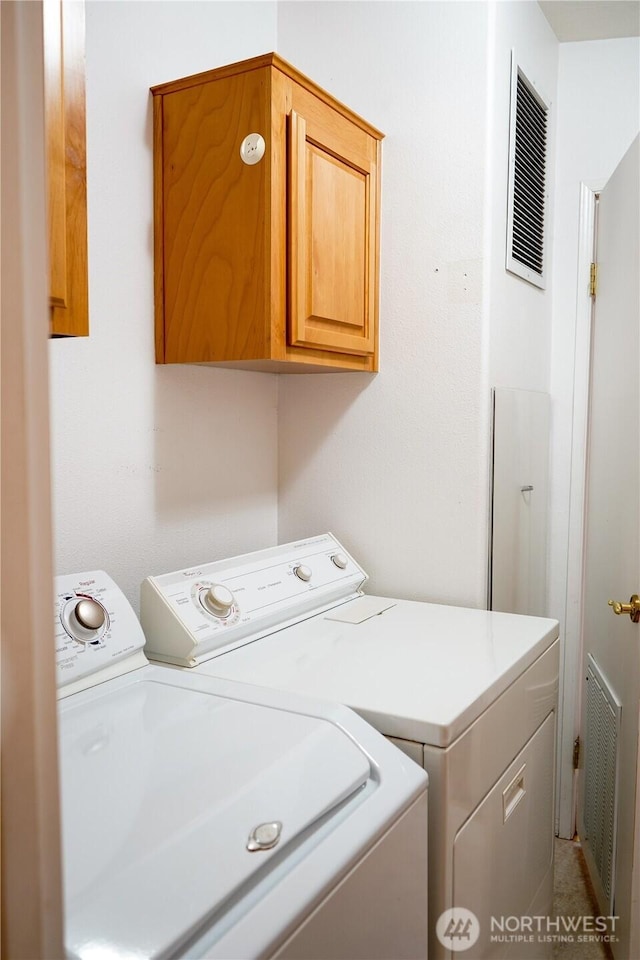 laundry area featuring washer and clothes dryer, visible vents, and cabinet space