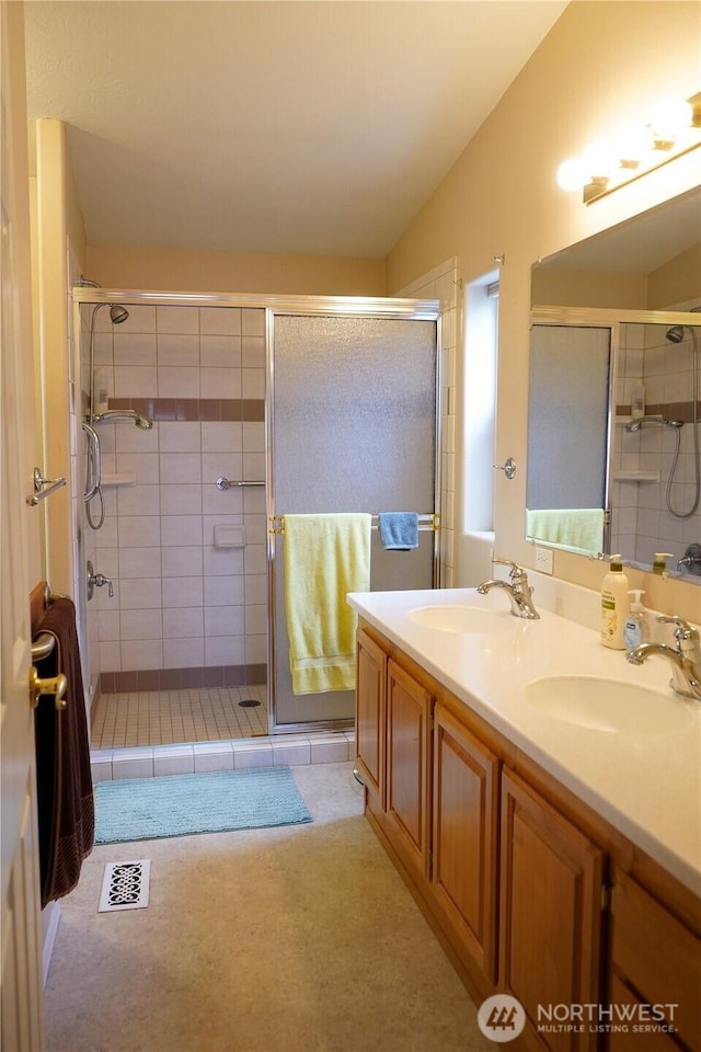 bathroom featuring a sink, visible vents, a shower stall, and vaulted ceiling