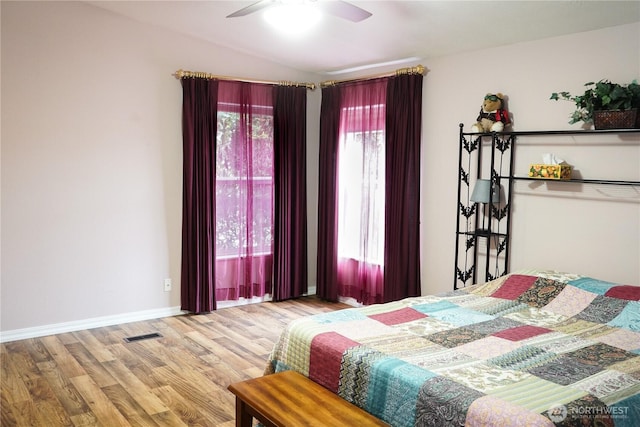 bedroom featuring visible vents, baseboards, vaulted ceiling, wood finished floors, and a ceiling fan