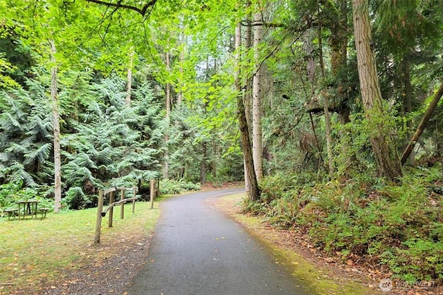 view of property's community featuring aphalt driveway and a view of trees