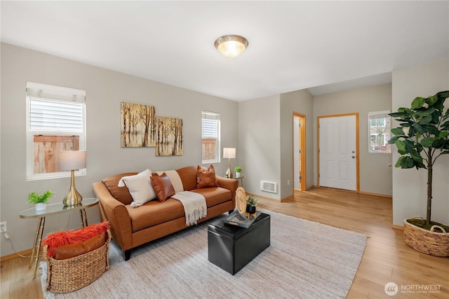 living room featuring light wood finished floors, visible vents, and baseboards