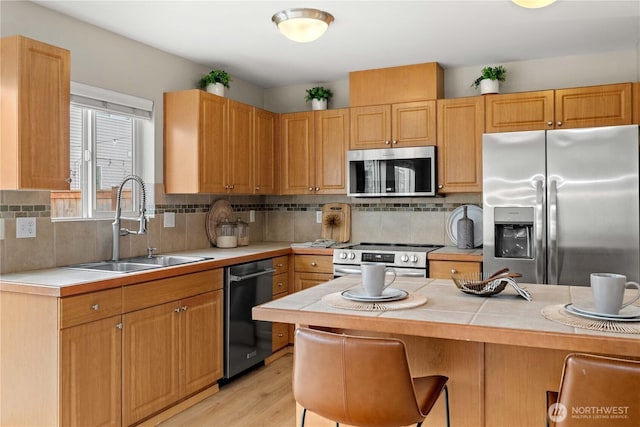 kitchen with a breakfast bar, tasteful backsplash, appliances with stainless steel finishes, and a sink