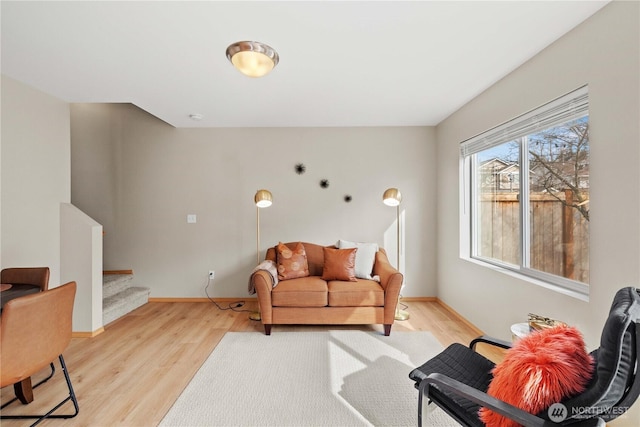 sitting room featuring stairway, baseboards, and light wood finished floors