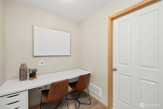 office with light wood-type flooring, visible vents, and built in study area