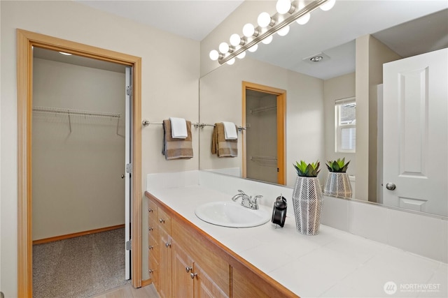 bathroom with vanity and a walk in closet