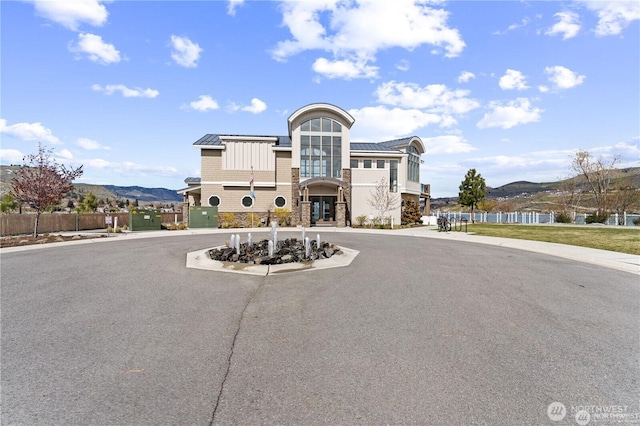 view of building exterior featuring aphalt driveway, fence, and a mountain view