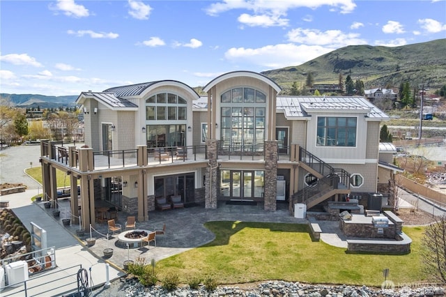 rear view of property with a fire pit, stairway, a standing seam roof, metal roof, and a patio