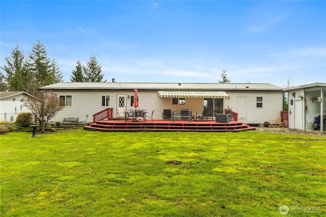 back of property with a wooden deck, a lawn, and metal roof