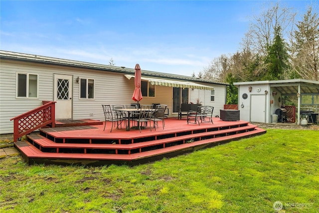 rear view of house featuring a shed, outdoor dining area, a yard, a deck, and an outbuilding