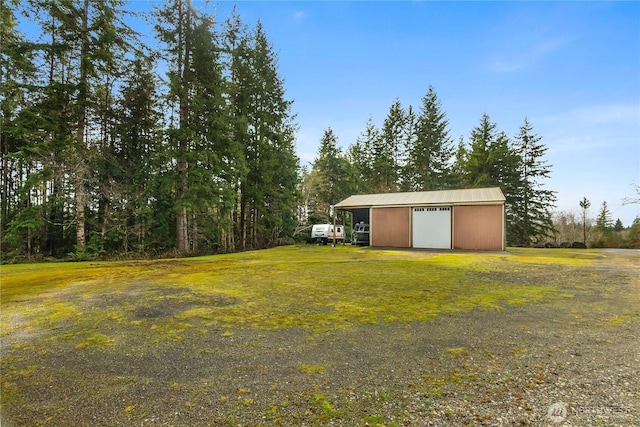 view of yard with a detached garage, an outbuilding, and driveway