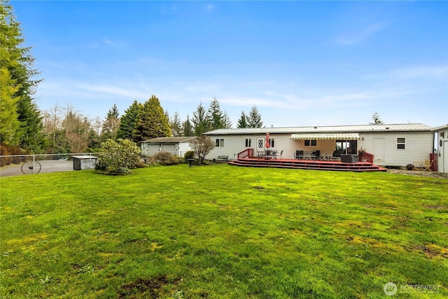 back of property featuring a lawn, metal roof, a deck, and fence