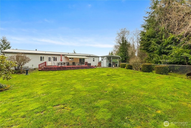 rear view of property featuring metal roof, a wooden deck, a yard, and fence