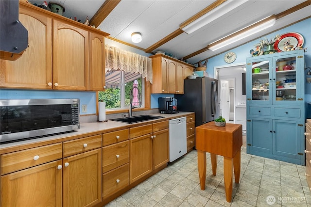 kitchen with stainless steel appliances, a sink, vaulted ceiling, light countertops, and brown cabinets