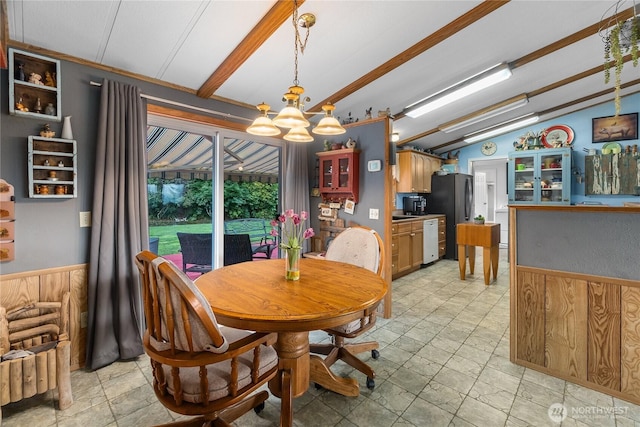 dining space featuring lofted ceiling with beams, a wainscoted wall, a chandelier, and wood walls