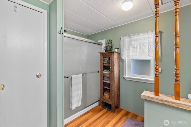 bathroom with wood finished floors and a shower stall