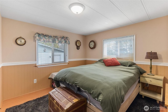 bedroom with a wainscoted wall and wood finished floors