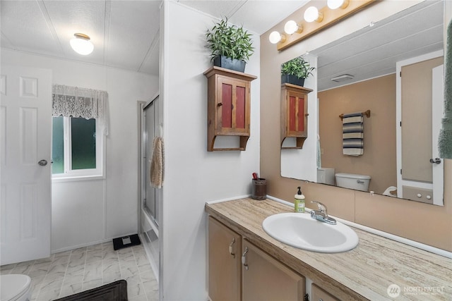 full bathroom featuring toilet, vanity, and bath / shower combo with glass door