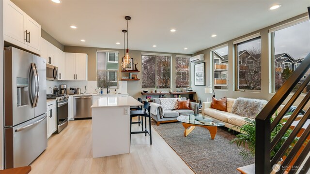 kitchen with light wood-type flooring, a breakfast bar, a wall unit AC, stainless steel appliances, and light countertops