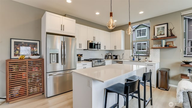 kitchen with light countertops, decorative backsplash, appliances with stainless steel finishes, white cabinetry, and a sink