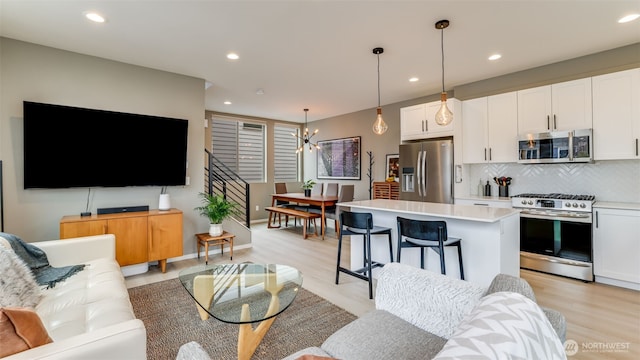 living area with a notable chandelier, recessed lighting, and light wood-style floors