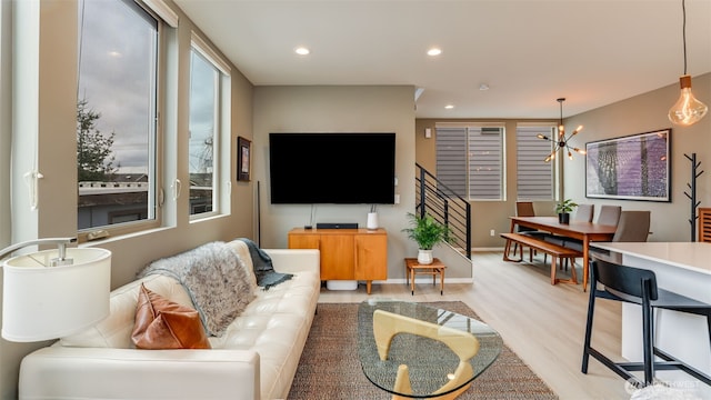 living room with light wood finished floors, baseboards, stairs, recessed lighting, and an inviting chandelier