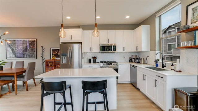 kitchen featuring light wood-style flooring, a sink, a kitchen breakfast bar, a center island, and stainless steel appliances