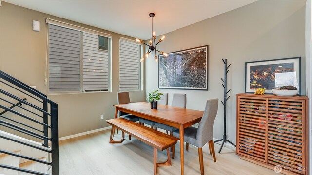 dining space featuring wood finished floors, wine cooler, an inviting chandelier, baseboards, and stairs