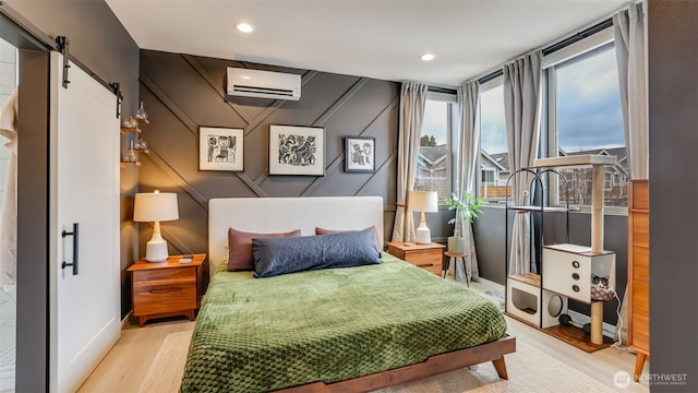 bedroom with recessed lighting, a barn door, wood finished floors, and a wall unit AC