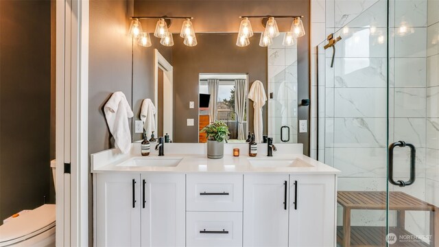 full bathroom with double vanity, toilet, a stall shower, and a sink