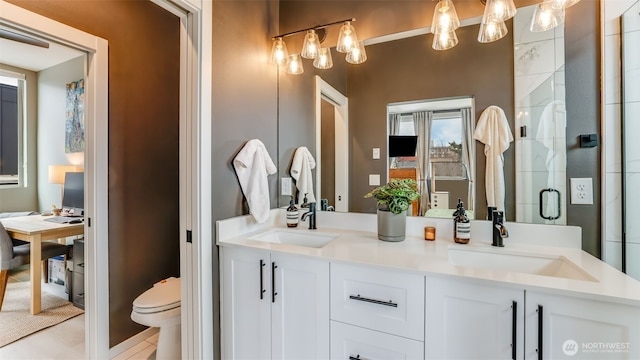 bathroom with a sink, toilet, double vanity, and a shower stall