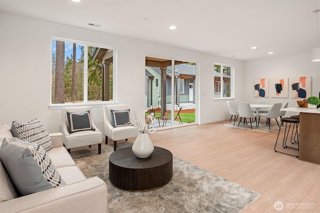 living room with recessed lighting, light wood-style floors, visible vents, and baseboards