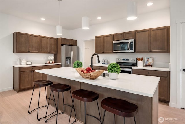 kitchen with light countertops, a breakfast bar area, light wood-type flooring, and appliances with stainless steel finishes