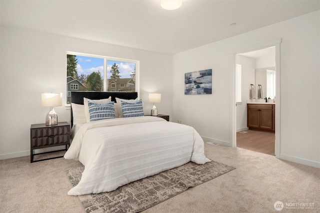 carpeted bedroom featuring ensuite bath and baseboards