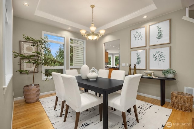 dining area with light wood finished floors, an inviting chandelier, baseboards, and a tray ceiling