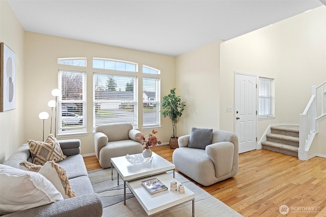 living room featuring light wood-style flooring, stairs, and baseboards