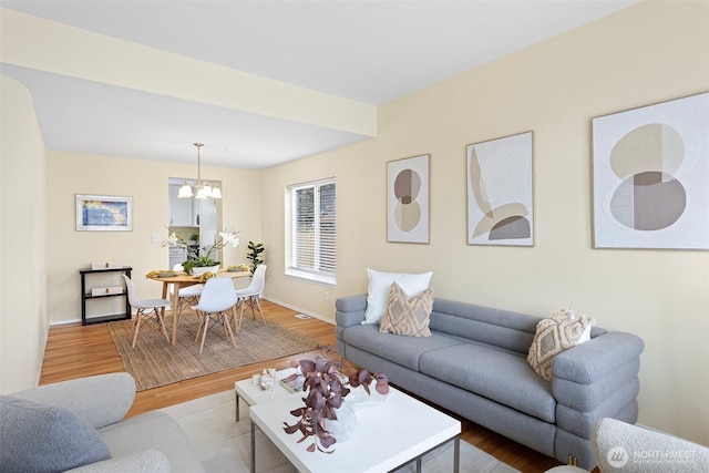 living room with a notable chandelier, baseboards, and light wood-style floors