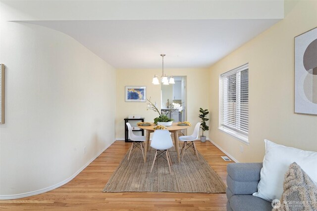 dining area with an inviting chandelier, light wood-style floors, visible vents, and baseboards